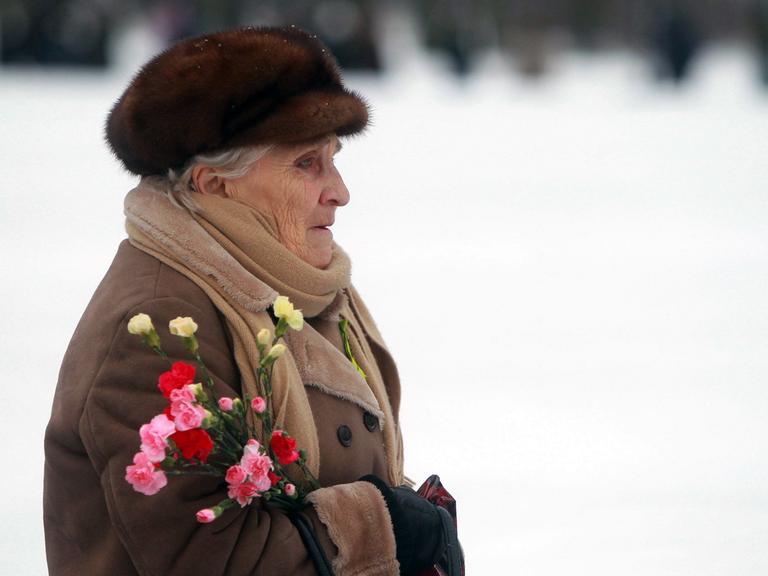 Eine alte Frau mit Blumen im Arm auf einer Gedenkveranstaltung in St. Petersburg zur Erinnerung an das Ende der Leningrader Blockade durch die Nazis, die von 1941-1944 dauerte.