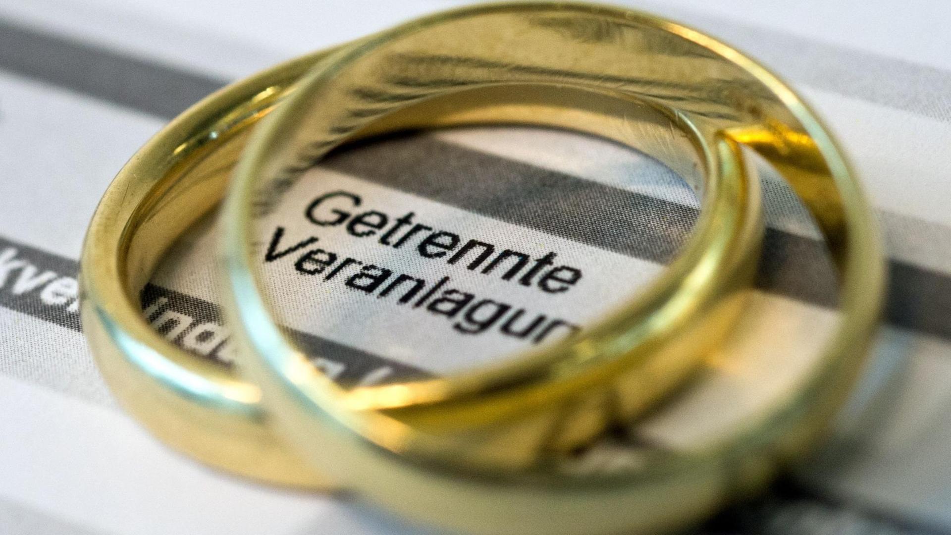 Goldene Eheringe liegen auf Formularen für die Steuererklärung. Goldene Eheringe liegen auf Formularen für die Steuererklärung.
