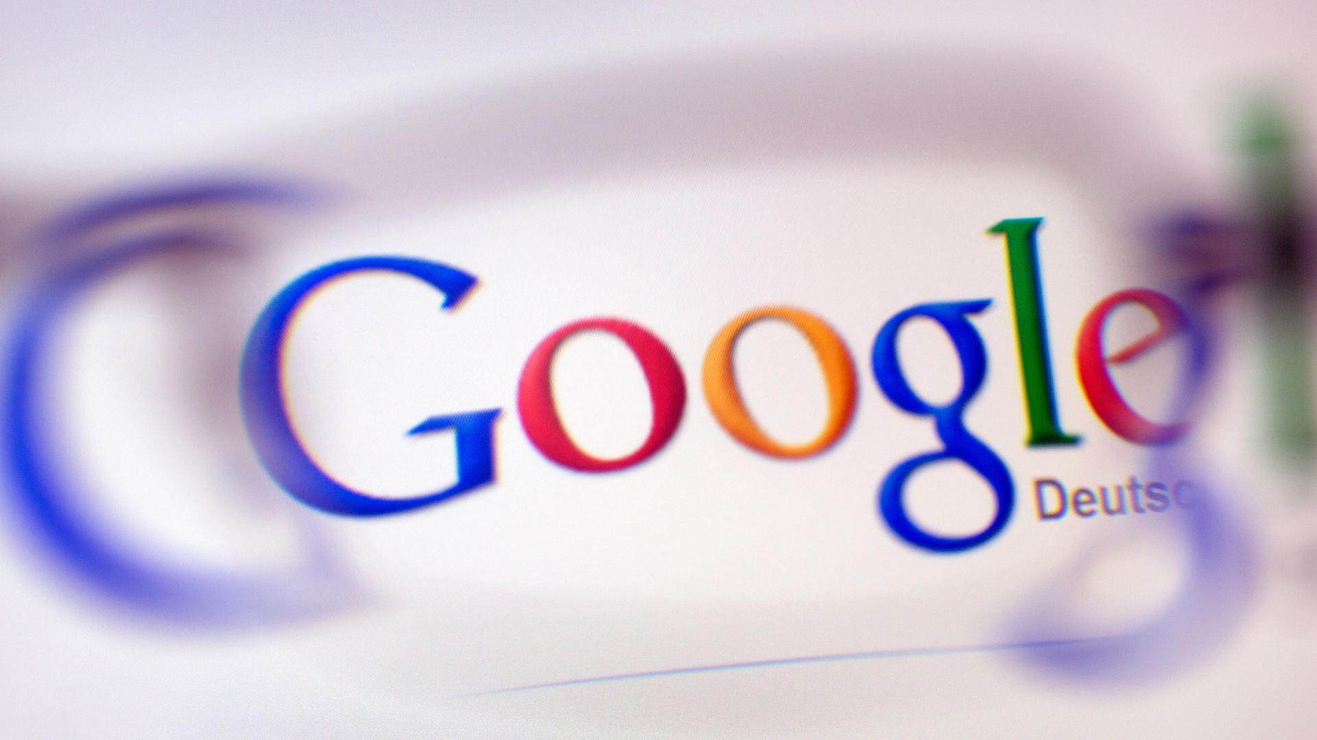 Das Google-Logo ist durch ein Brillenglas auf einem Bildschirm zu sehen.