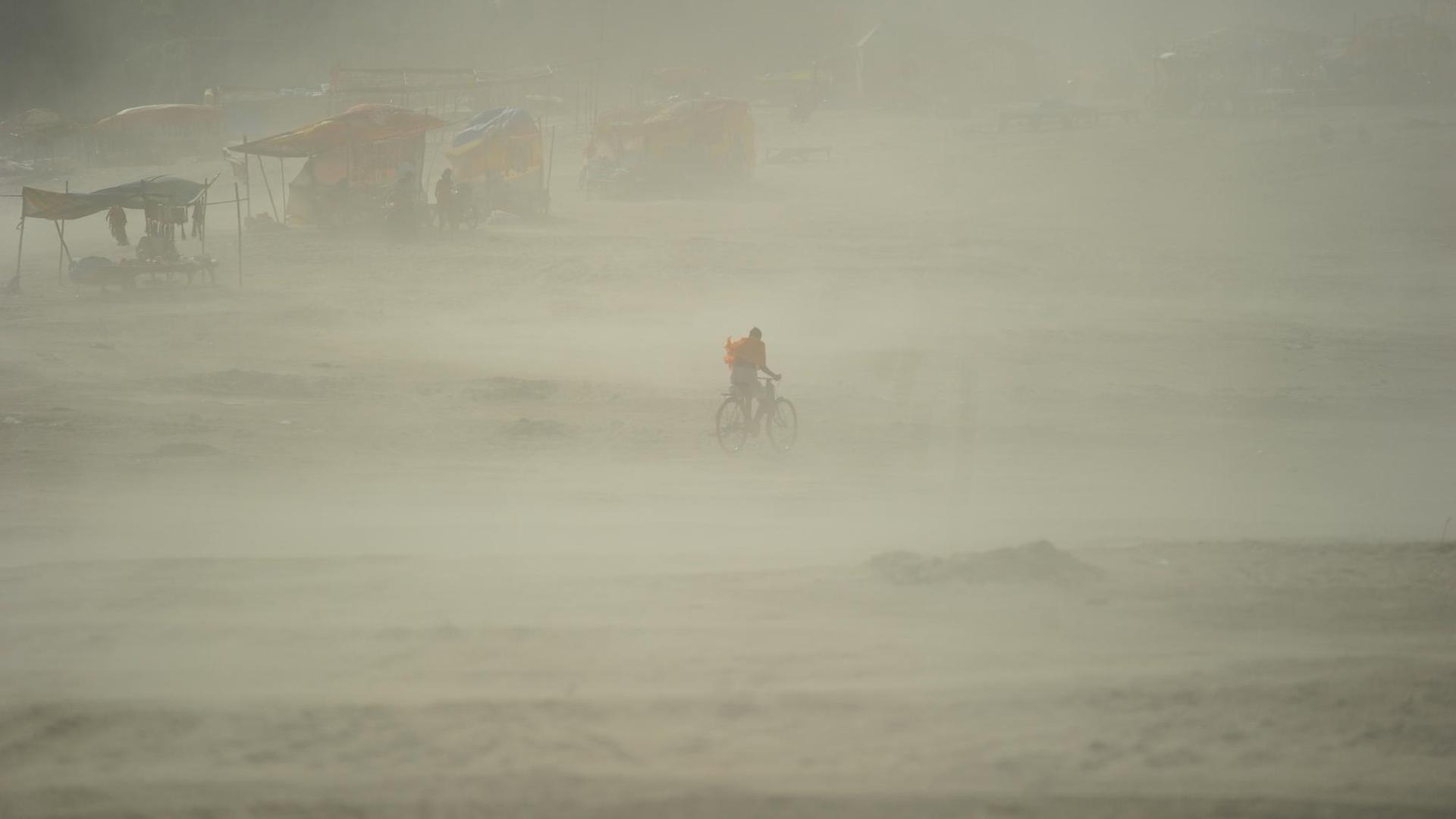 Ein Mann fährt mit dem Fahrrad durch einen Sandsturm.