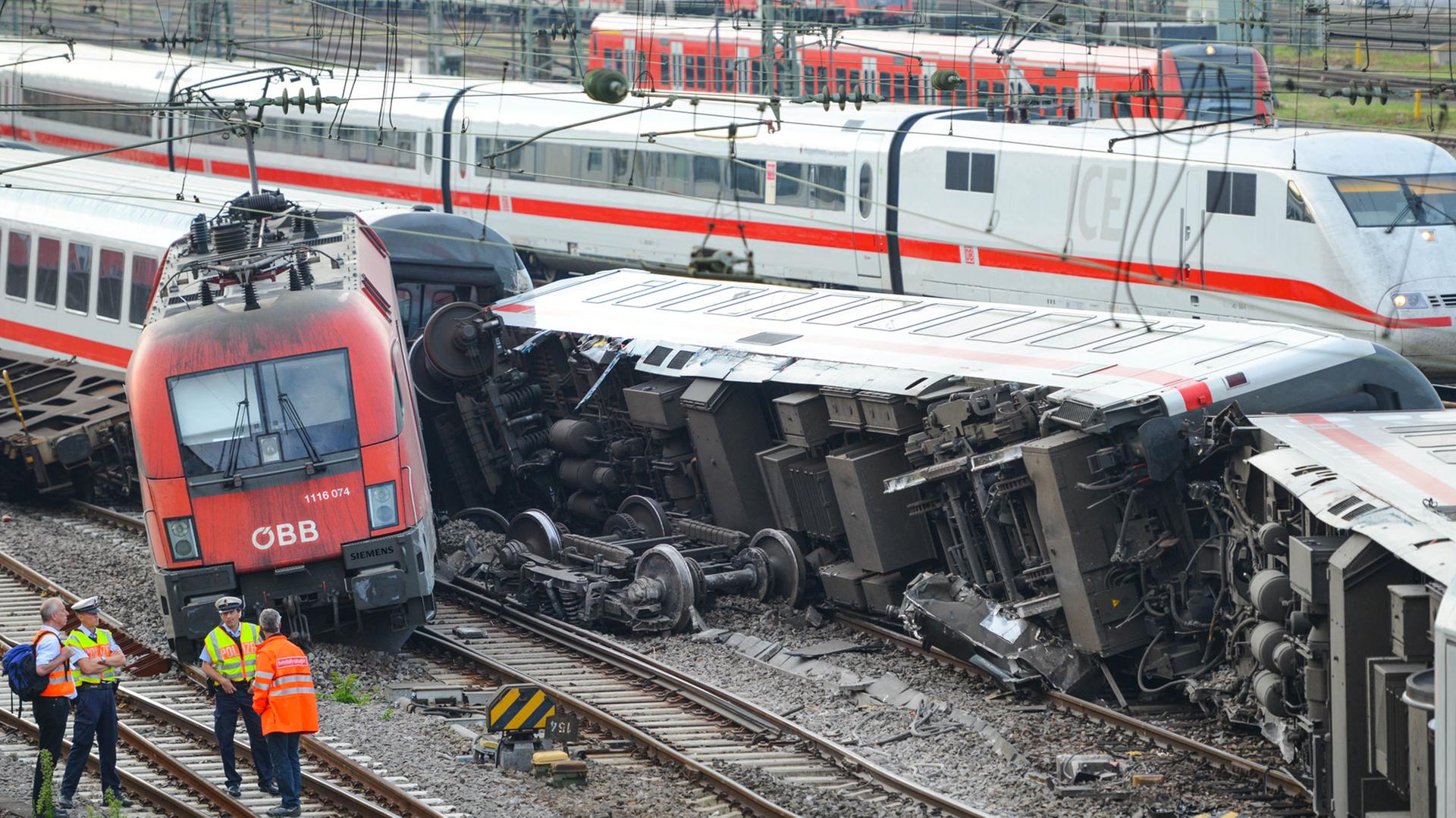 Polizeibeamte stehen am 02.08.2014 in Mannheim (Baden-Württemberg) am Hauptbahnhof vor umgekippten Waggons eines Eurocitys und der Lok eines Güterzugs. Polizeibeamte stehen am 02.08.2014 in Mannheim (Baden-Württemberg) am Hauptbahnhof vor umgekippten Waggons eines Eurocitys und der Lok eines Güterzugs.