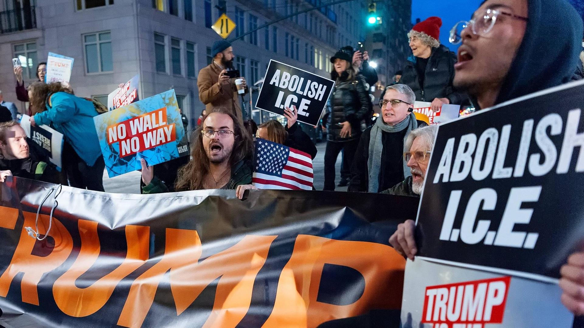 Empörte Aktivisten halten Transparente mit Anti-Trump-Parolen in die Luft.