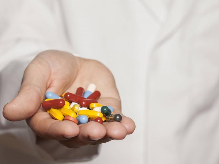 Ein Arzt hält Tabletten in der Hand.