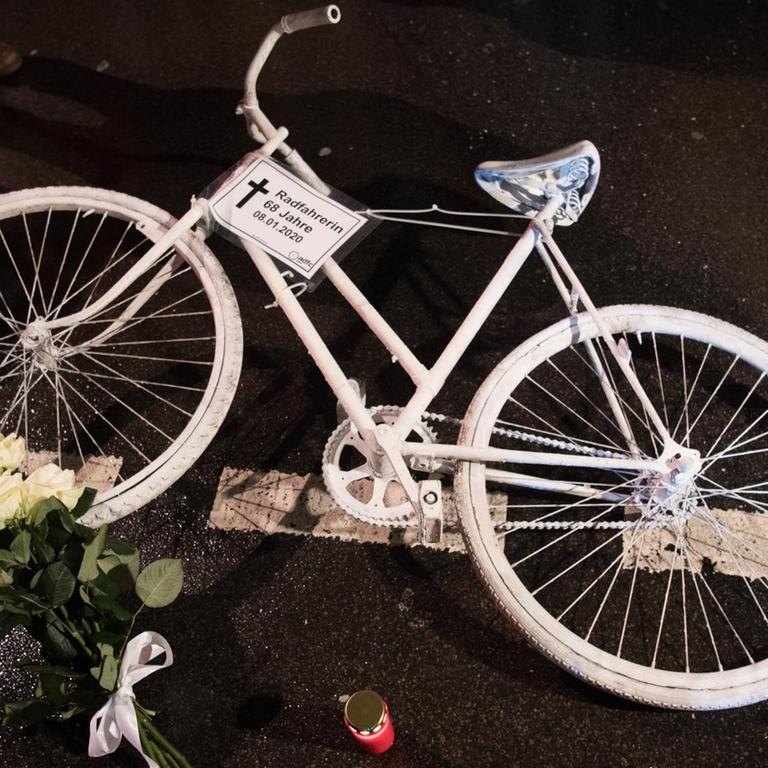 Ein weißes Rad und Blumen liegen auf einer Straße.