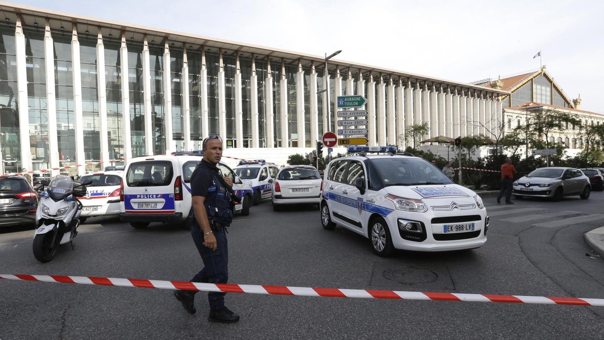 Ein Polizist steht an einer Absperrung vor dem Bahnhof in Marseille