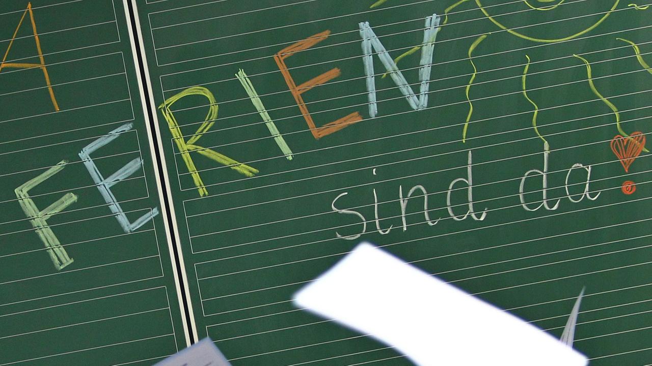 Schüler einer ersten Klasse halten am 29.07.2014 in einer Grundschule in Kaufbeuren (Bayern) ihre Zeugnisse vor einer Tafel mit der Aufschrift "Hurra Ferien sind da". 