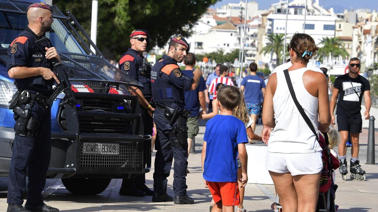 Zu sehen sind Passanten und spanische Polizisten am 18.8.2017 im Urlaubsort Cambrils.