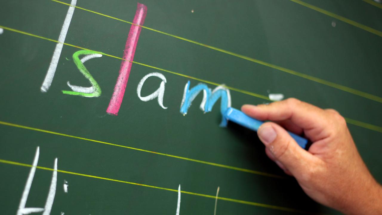 Ein Lehrer schreibtwährend des Religionsunterrichts das Wort "Islam" an die Tafel.