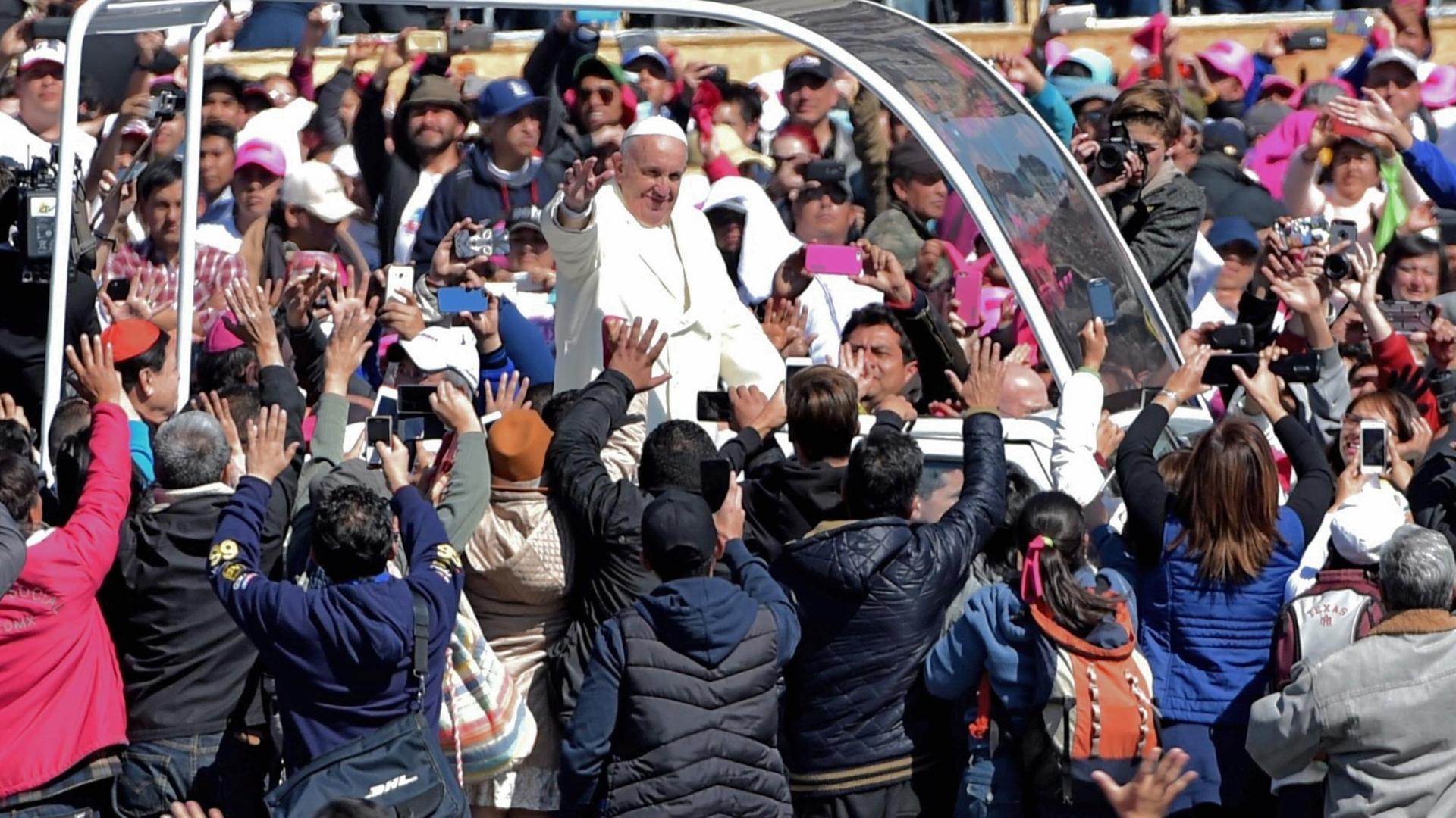 Papst Franziskus wird bei seiner Fahrt durch die Straßen von Mexiko-Stadt von tausenden Menschen umringt und bejubelt.