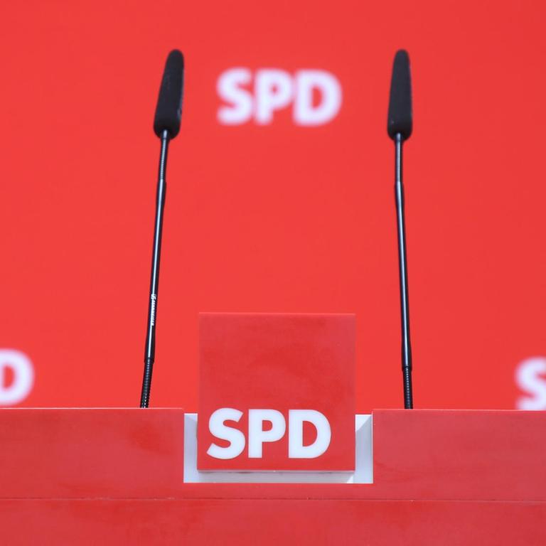 Drei SPD-Logos sind im Hintergrund eines Rednerpultes zu sehen.