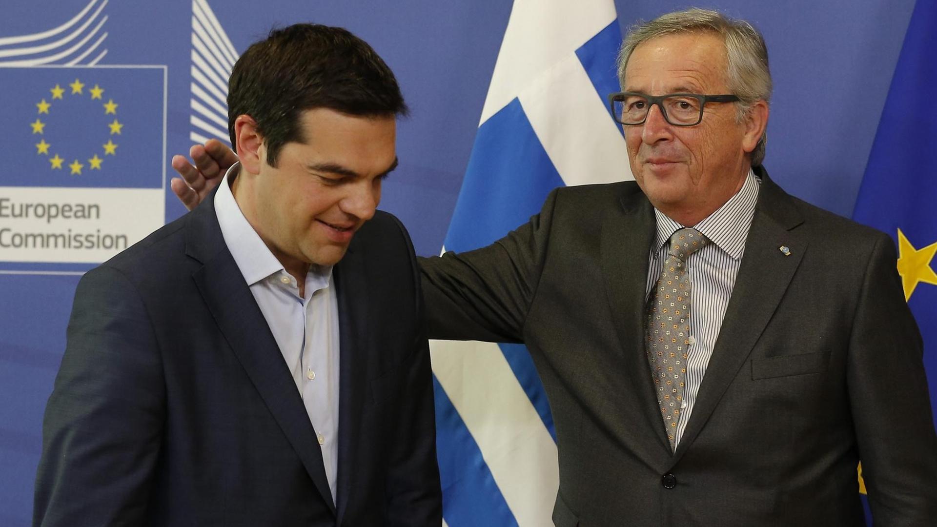 Jean-Claude Juncker begrüßt Alexis Tsipras in Brüssel. Er legt ihm die Hand auf die Schulter.