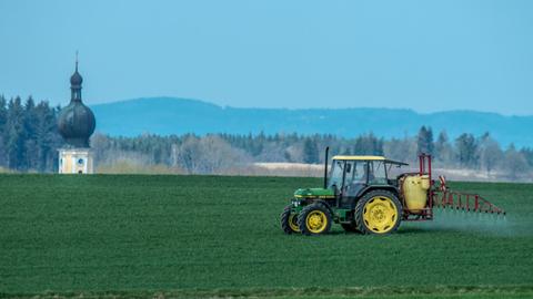 Mit einem Traktor wird nahe Sallach im Landkreis Straubing-Bogen (Bayern) Pflanzenschutzmittel auf ein Feld gespritzt.
