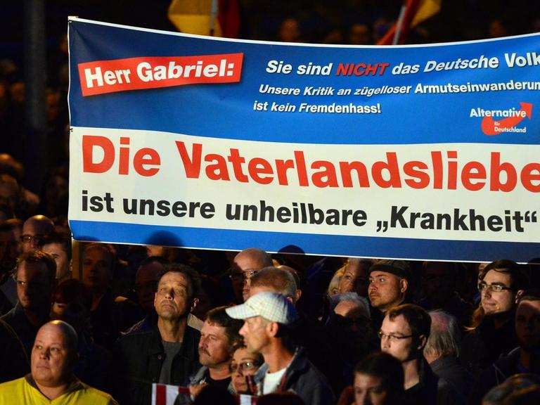 Demonstranten protestieren mit einem Banner und der Aufschrift "Herr Gabriel: Sie sind nicht das Volk! Unsere Kritik an zügelloser Armutseinwanderung ist kein Fremdenhass! Die Vaterlandsliebe ist unsere unheilbare 'Krankheit'!" am 07.10.2015 in Erfurt (Thüringen) gegen die Asylpolitik. Die rechtskonservative AfD hatte zur Demonstration aufgerufen. Die Polizei sprach zum Auftakt der Kundgebung von 5000 Teilnehmern, die Zahl der Gegendemonstranten wurde mit 800 angegeben.