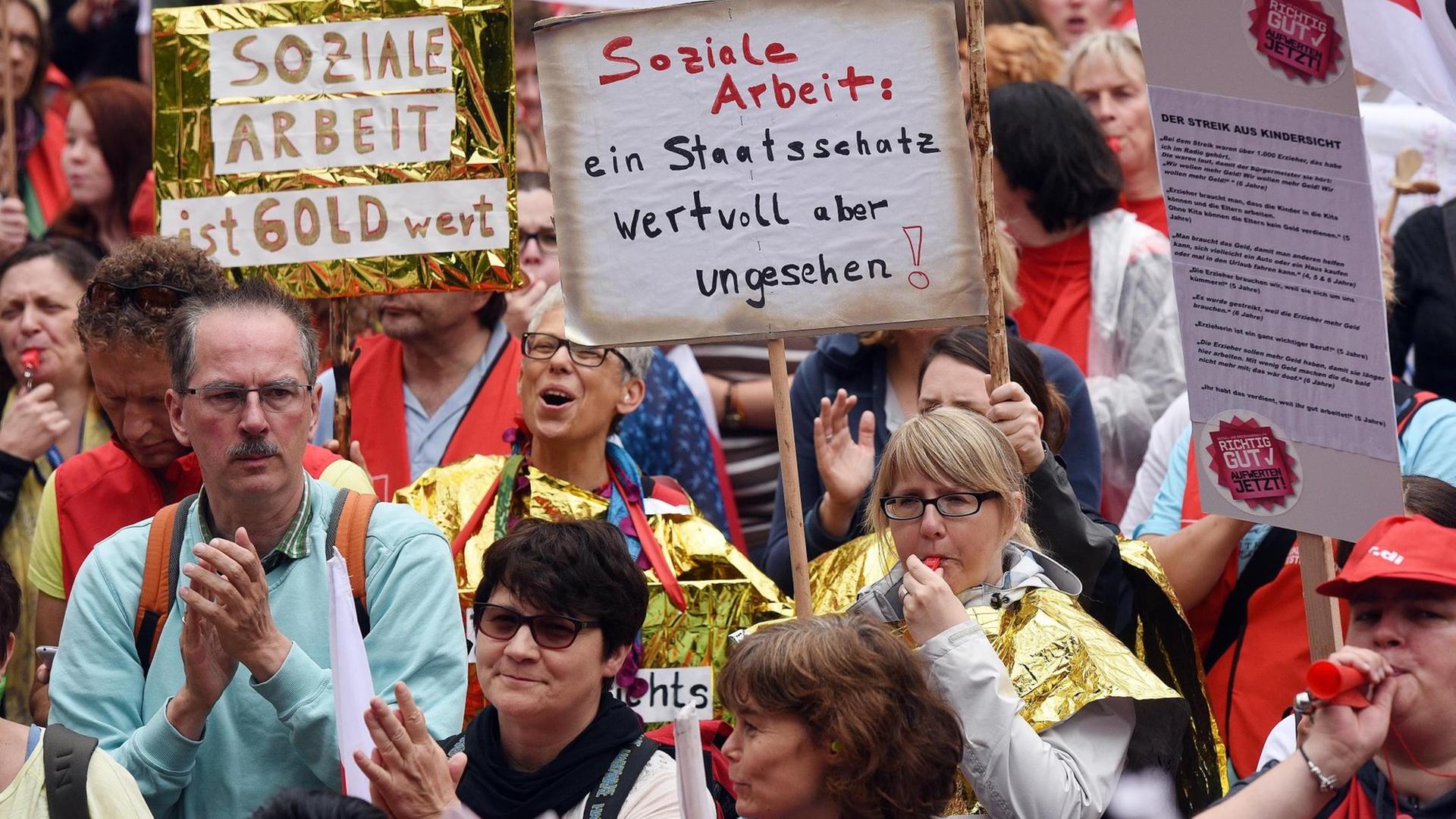 Teilnehmer halten am 13.06.2015 in Köln (Nordrhein-Westfalen) bei einer Demonstration aus Solidarität mit den Beschäftigten der kommunalen Sozial- und Erziehungsdienste ihre Schilder hoch.