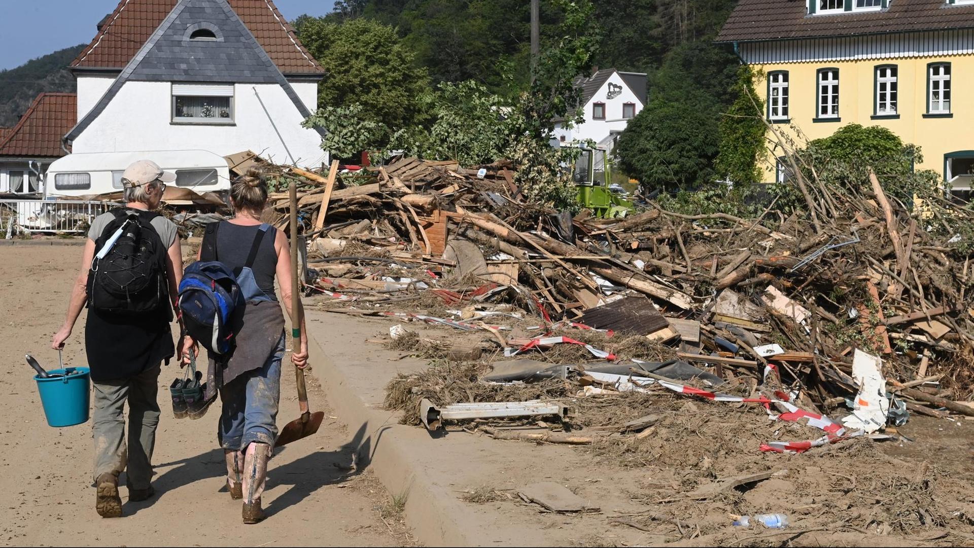 Helfer mit Schaufeln und Eimer auf einer zerstörten Strasse in Kreuzberg nach der Hochwasserkatastrophe. NRW, 20.07.2021.