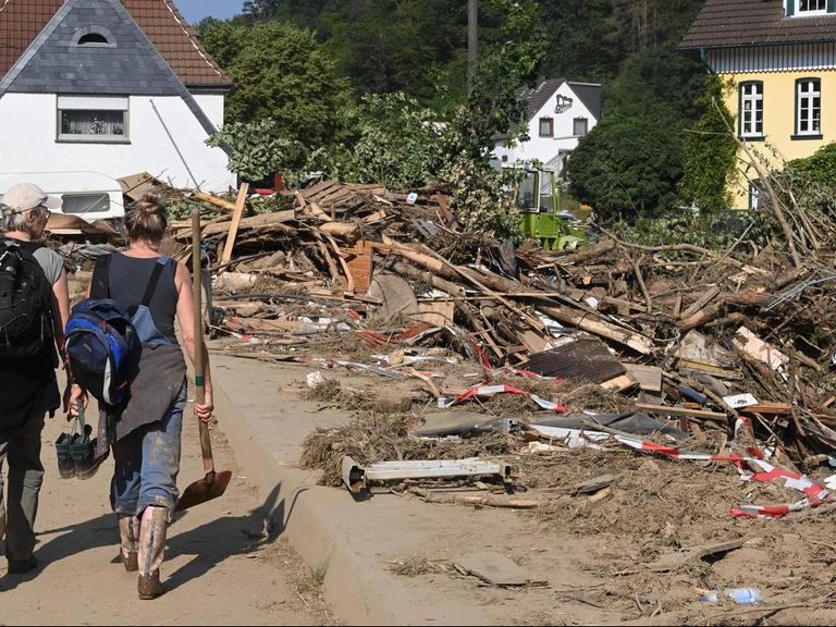Helfer mit Schaufeln und Eimer auf einer zerstörten Strasse in Kreuzberg nach der Hochwasserkatastrophe. NRW, 20.07.2021.