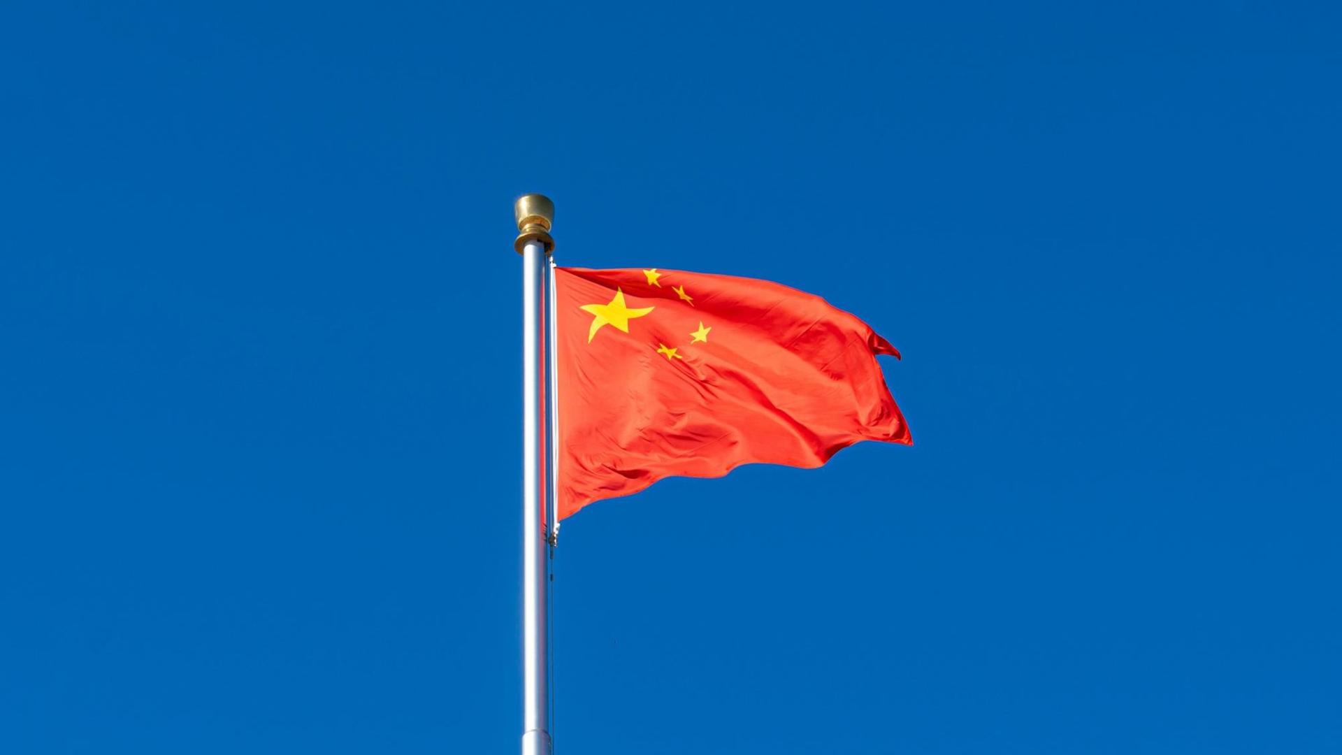 Die rote Flagge der Volksrepublik China vor blauem Himmel.