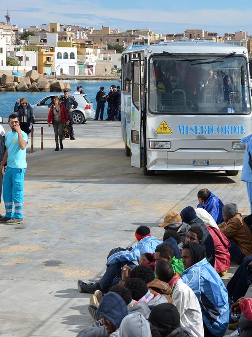 Flüchtlinge auf der Insel Lampedusa warten darauf, mit einer Fähre nach Sizilien gebracht zu werden.