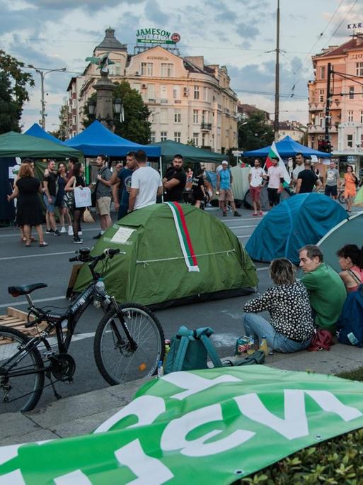 Demonstranten sitzen am Straßenrand und blockieren mit aufgeschlagenen Zelten die Straßen.