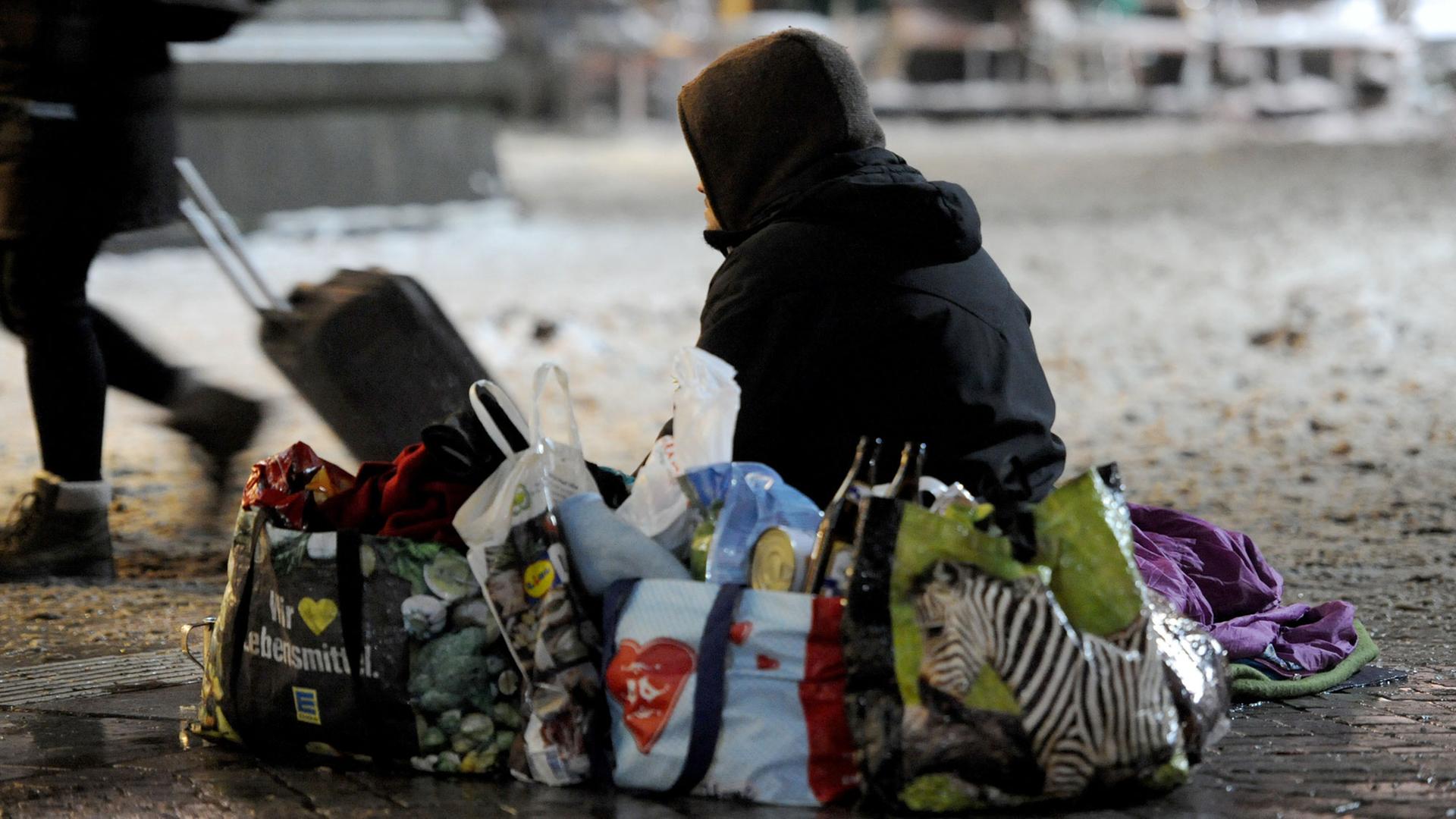 Ein obdachloser Mann sitzt im Winter auf dem Vorplatz des Hauptbahnhofes in Bremen.