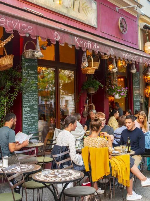 Menschen sitzen an Tischen draußen vor dem Restaurant Knofi in der bei Touristen beliebten Bergmannstraße in Berlin-Kreuzberg. Verwendung weltweit, Keine Weitergabe an Wiederverkäufer.