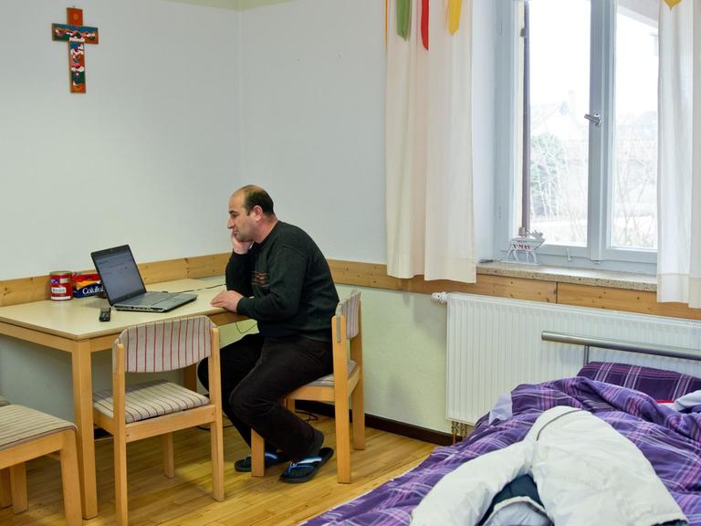 Der syrische Flüchtling Youssef sitzt am 10.03.2015 in seinem Zimmer im Pfarramt der evangelischen Kirchengemeinde Bad Rodach (Bayern) an einem gebrauchten PC der Kirchengemeinde. Der gelernte Bäcker lebt im Kirchenasyl. Seit fünf Wochen bietet ihm die evangelische Kirchengemeinde Bad Rodach Schutz.