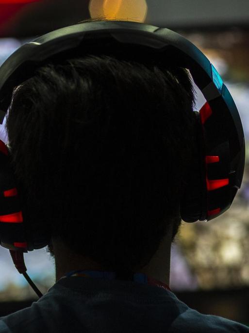 Ein Gamer mit Kopfhörern von hinten vor dem Bildschirm im Convention Center in Los Angeles.