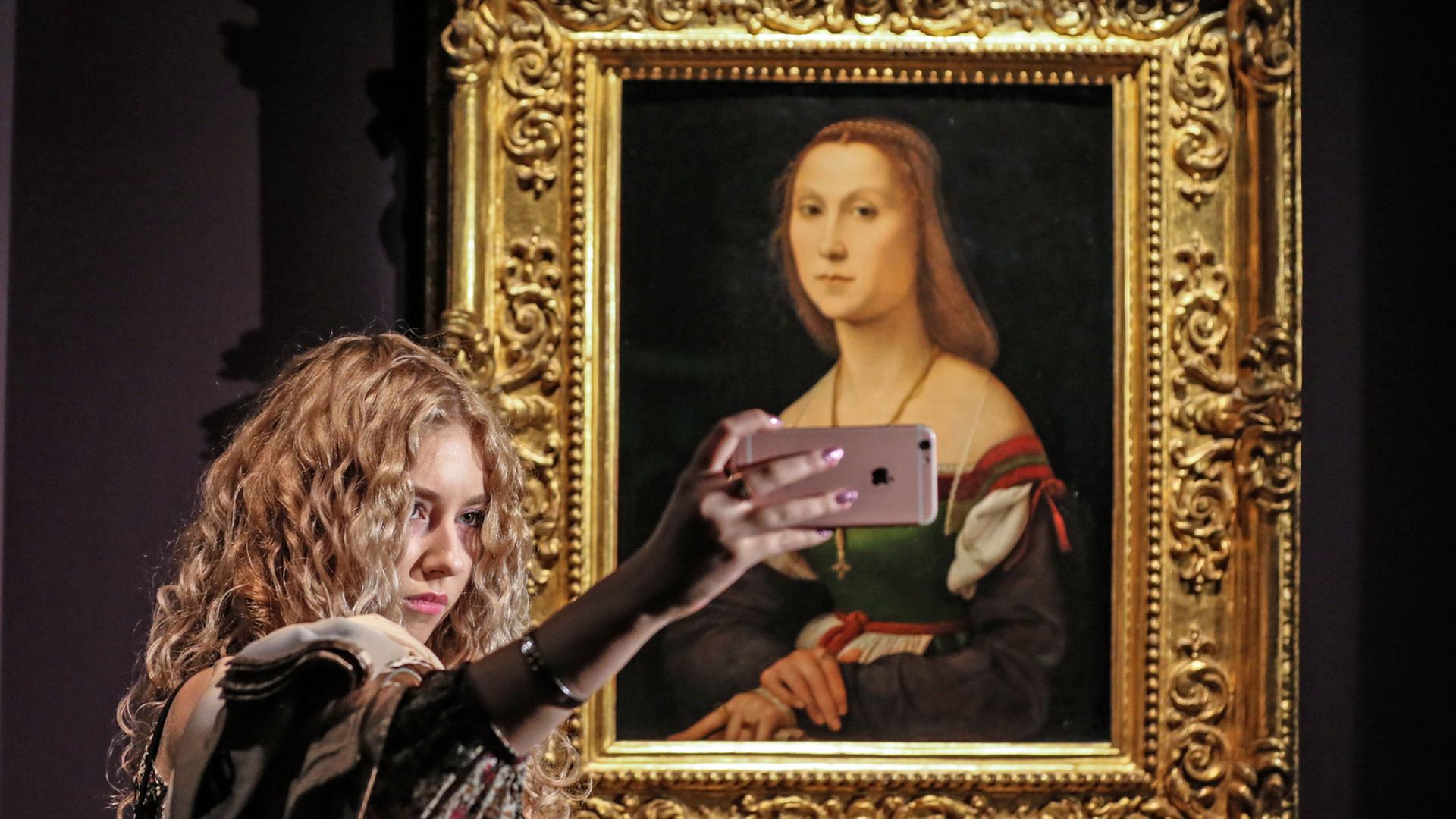 Eine Frau macht mit dem Smartphone ein Selfie vor Raphaels "Porträt einer jungen Frau" von 1507, zu sehen im September 2016 im Puschkin-Museum in Moskau.