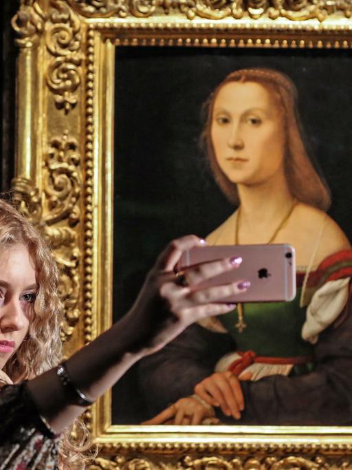 Eine Frau macht mit dem Smartphone ein Selfie vor Raphaels "Porträt einer jungen Frau" von 1507, zu sehen im September 2016 im Puschkin-Museum in Moskau.