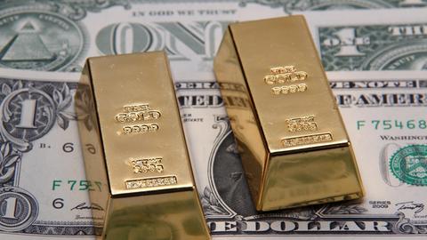 Zwei 200 Gramm schwere Goldbarren vor Dollarnoten | Verwendung weltweit