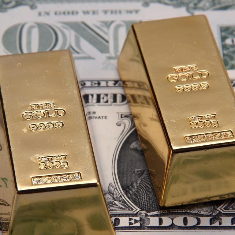 Zwei 200 Gramm schwere Goldbarren vor Dollarnoten | Verwendung weltweit