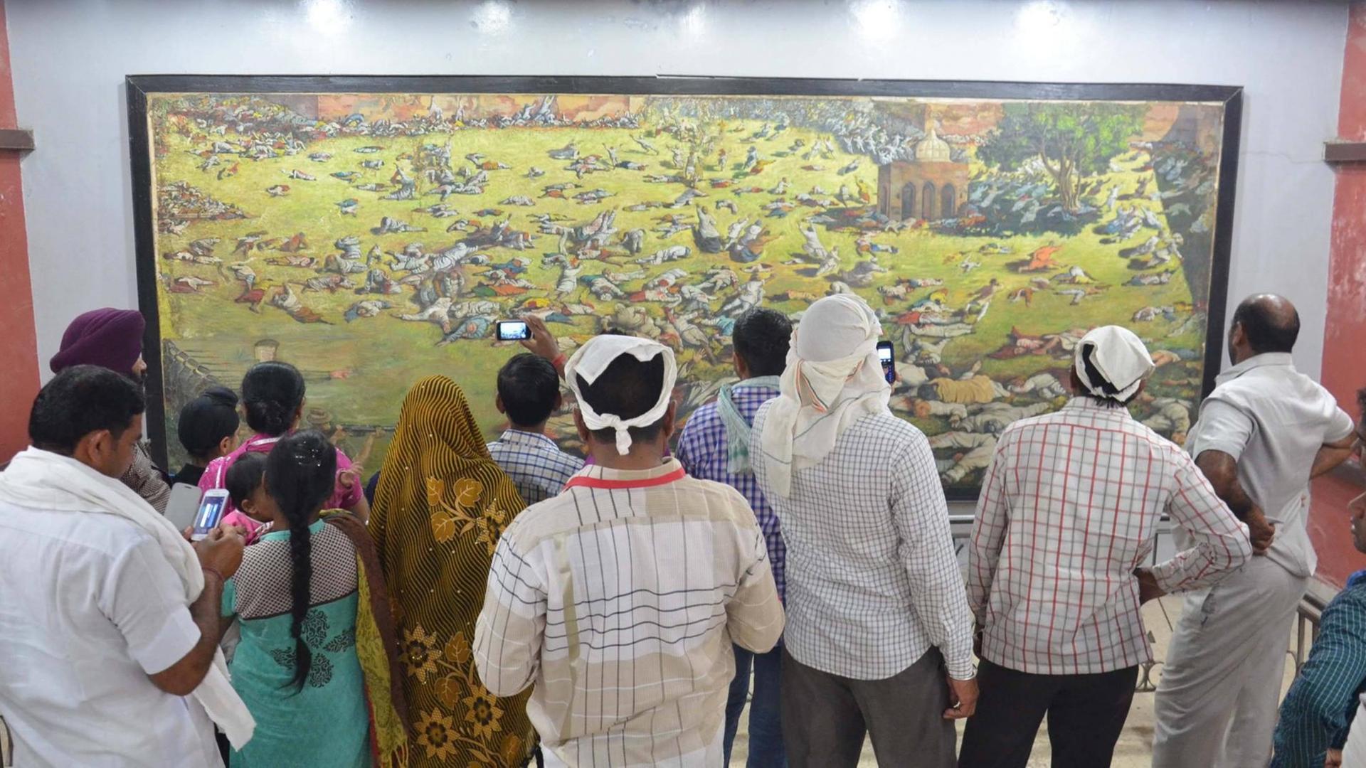 Besucher schauen auf ein Gemälde, das das Massaker im Park Jallianwala Bagh in Amritsar am 13. April 1919 darstellt.