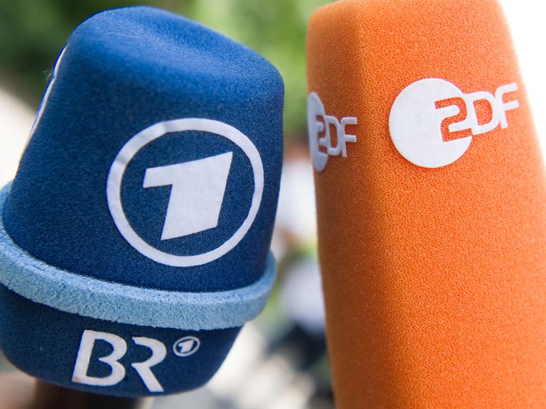 Fernsehmikrofone mit den Logos von ARD und ZDF stehen vor Beginn einer Pressekonferenz nebeneinander.