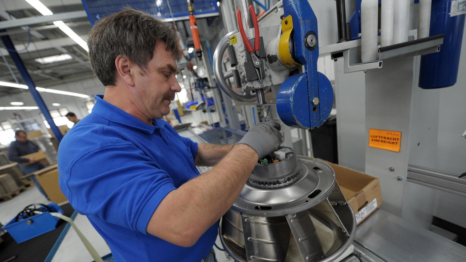 Ein Arbeiter montiert am 29.10.2012 im Werk 4 der Ziehl-Abegg AG in Künzelsau (Baden-Württemberg) einen Ventilator. Foto: Marijan Murat/dpa | Verwendung weltweit