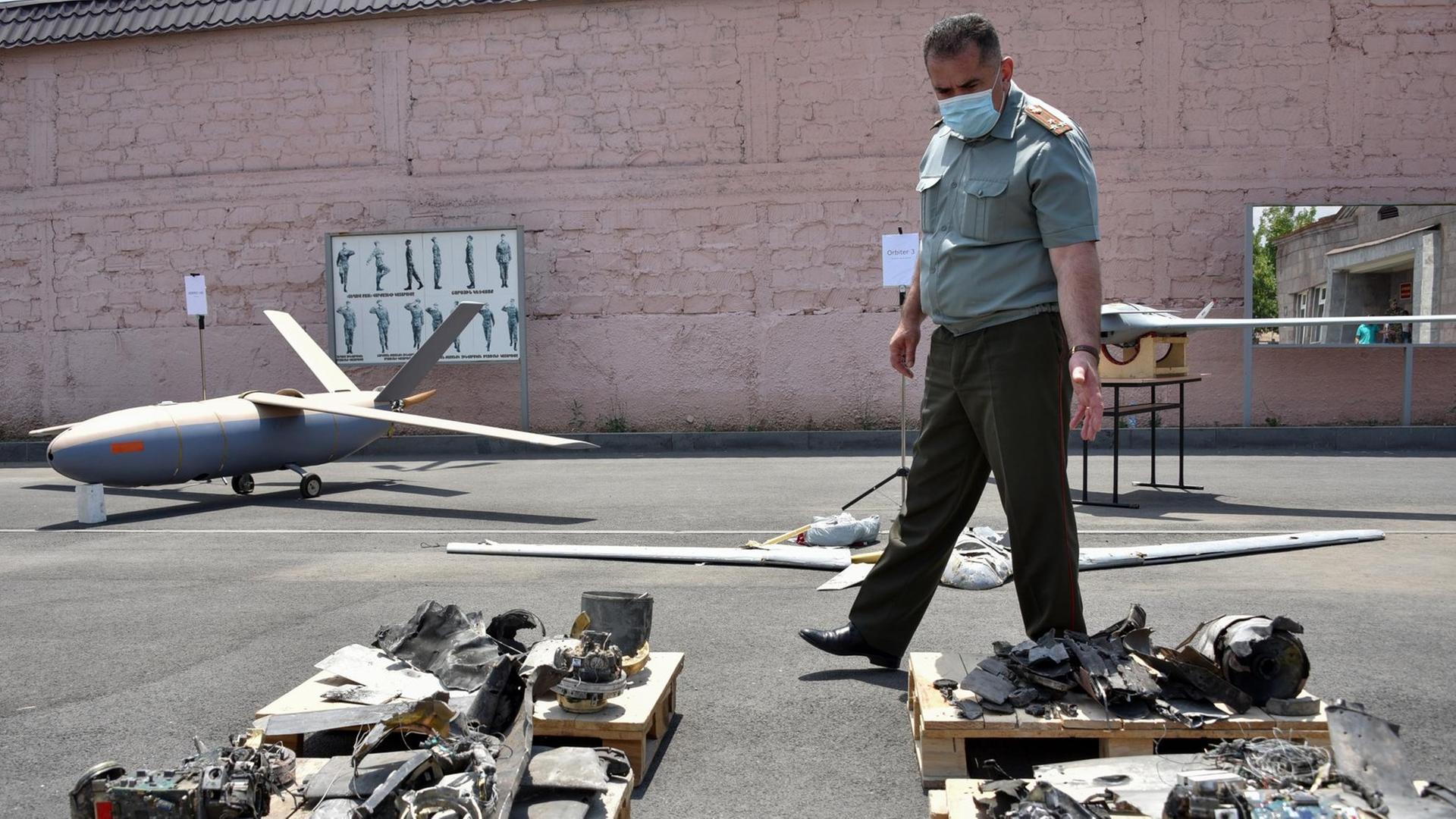 Ein Beamter geht am 21. Juli 2020 in Eriwan zwischen Objekten umher, die Armenien bei den jüngsten bewaffneten Zusammenstößen an der armenisch-aserbaidschanischen Grenze als erbeutete und abgeschossene aserbaidschanische Drohnen präsentiert hat.