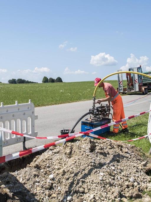 Ein Arbeiter verlegt bei Degerndorf in Bayern ein Glasfaserkabel