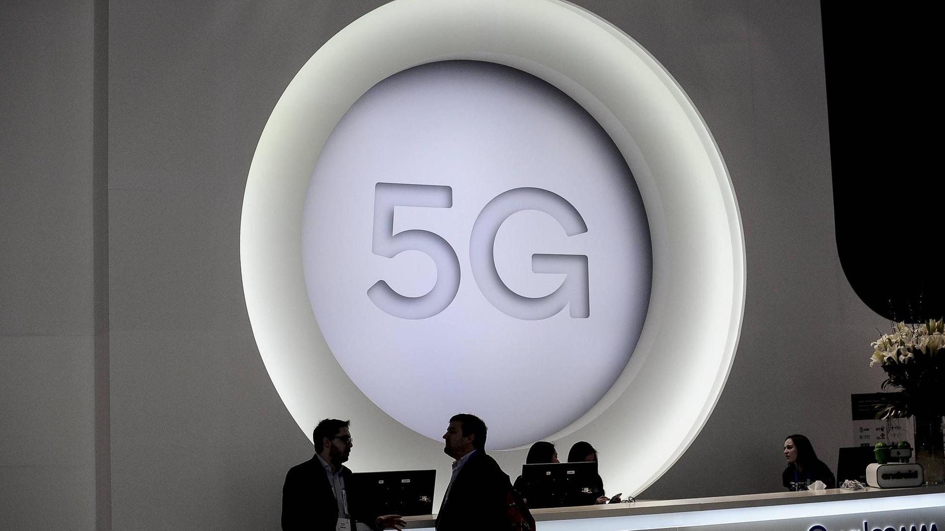 Menschen stehen beim Mobile World Congress in Barcelona vor einem riesigen 5G-Logo.
