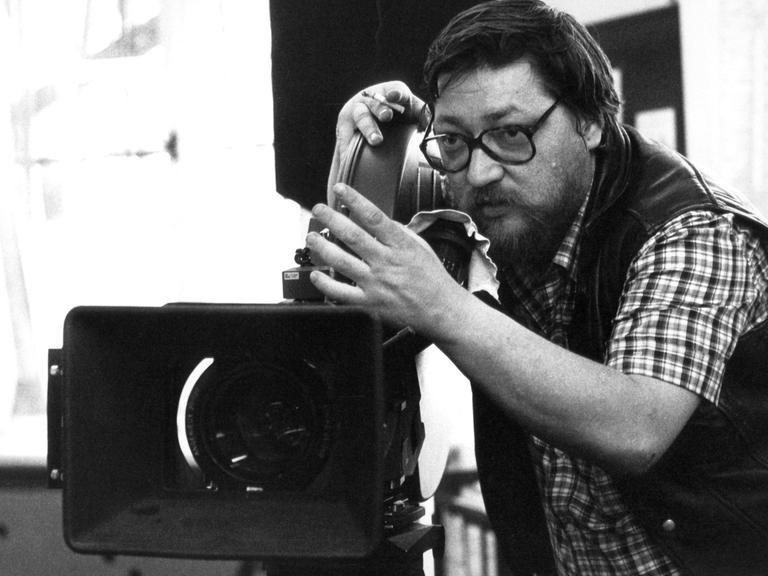 Schwarz-weißes Foto des Regisseurs Rainer Werner Fassbinder bei Dreharbeiten.