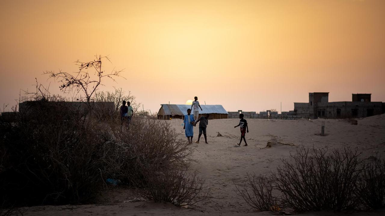Kinder spielen im Armenviertel Tarhil der Hauptstadt Nouakchott dem Sonnenuntergang entgegen