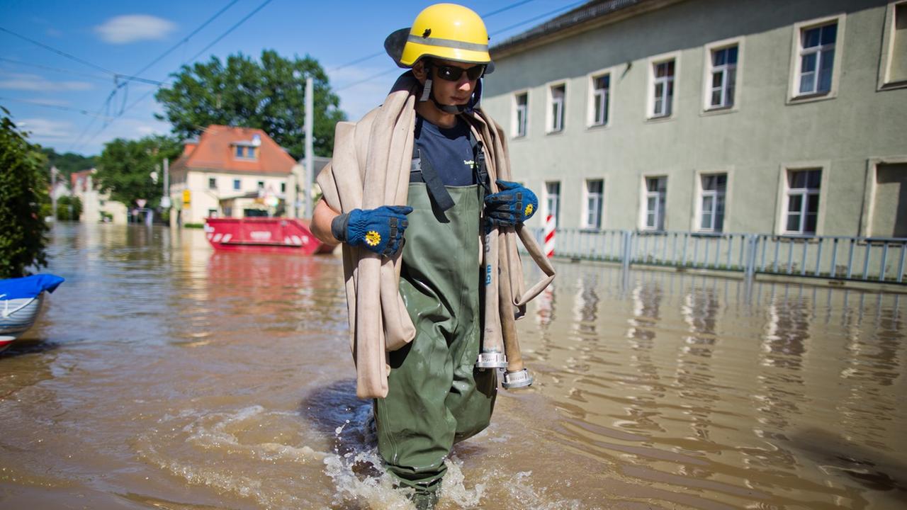 Ein THW-Helfer (Technisches Hilfswerk) trägt am 05.06.2013 im Dresdner Stadtteil Laubegast (Sachsen) einen Schlauch durch das ansteigende Hochwasser der Elbe. Foto: Michael Kappeler/dpa Ein THW-Helfer (Technisches Hilfswerk) trägt am 05.06.2013 im Dresdner Stadtteil Laubegast (Sachsen) einen Schlauch durch das ansteigende Hochwasser der Elbe. Foto: Michael Kappeler/dpa