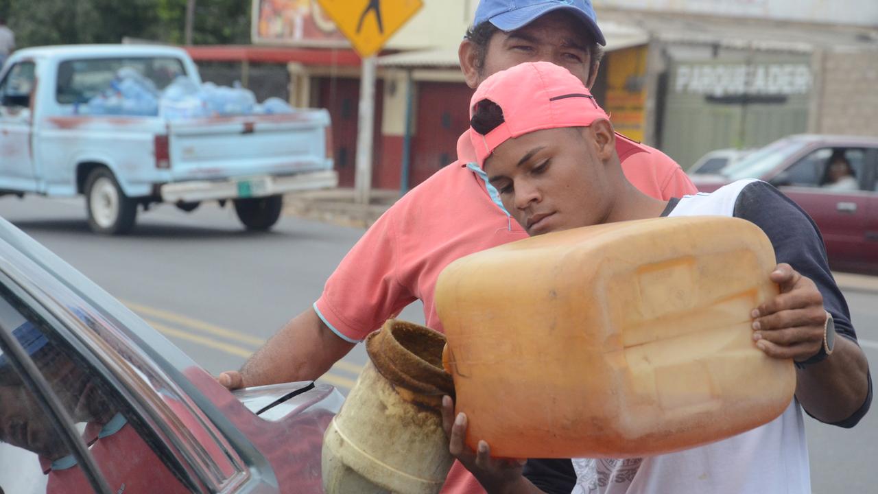 Ein junger Mann füllt aus Venezuela geschmuggeltes Benzin an einer Straße in Maicao (Kolumbien) in ein Fahrzeug. In der Grenzstadt blüht der Schwarzmarkt mit Benzin.