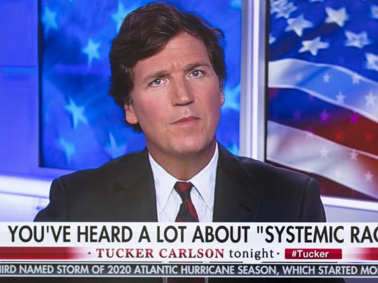 Tucker Carlson in seiner TV-Show, in einem Spruchband steht "Sie haben viel über 'systematischen Rassismus' gehört."