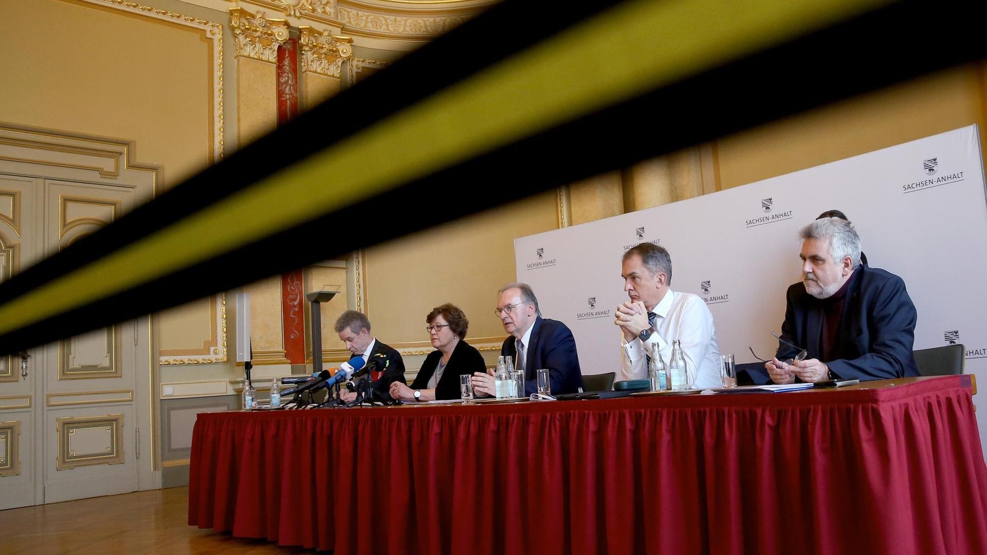 Teile von Sachsen-Anhalts Landesregierung bei einer Pressekonferenz, wegen der Coronakrise hinter einem Absperrband