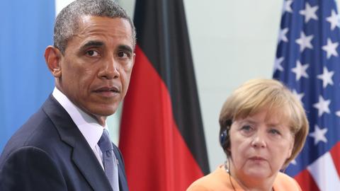 Barack Obama und Angela Merkel. Im Hintergrund: die Flaggen Deutschlands und der USA.