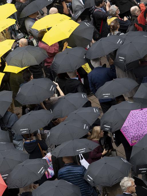 dpatopbilder - 17.10.2019, Hessen, Frankfurt/Main: Mit Regenschirmen beteiligen sich zahlreiche Menschen auf der Buchmesse an einer Mahnwache für die Meinungsfreiheit. Dabei ging es in erster Linie um ein Zeichen der Solidarität für den in China inhaftierten Autor Gui Minhai. Foto: Boris Roessler/dpa | Verwendung weltweit