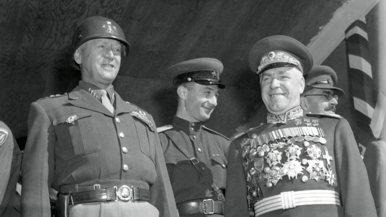 General George S. Patton (left) and Soviet Marshall Gregory Zhukov review troops in Berlin. Soldiers of four nations marched in a parade to celebrate the 