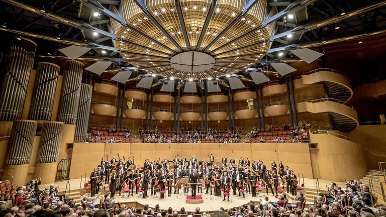 Das Orchester in großer Besetzung nimmt stehend Beifall in der Kölner Philharmonie an.