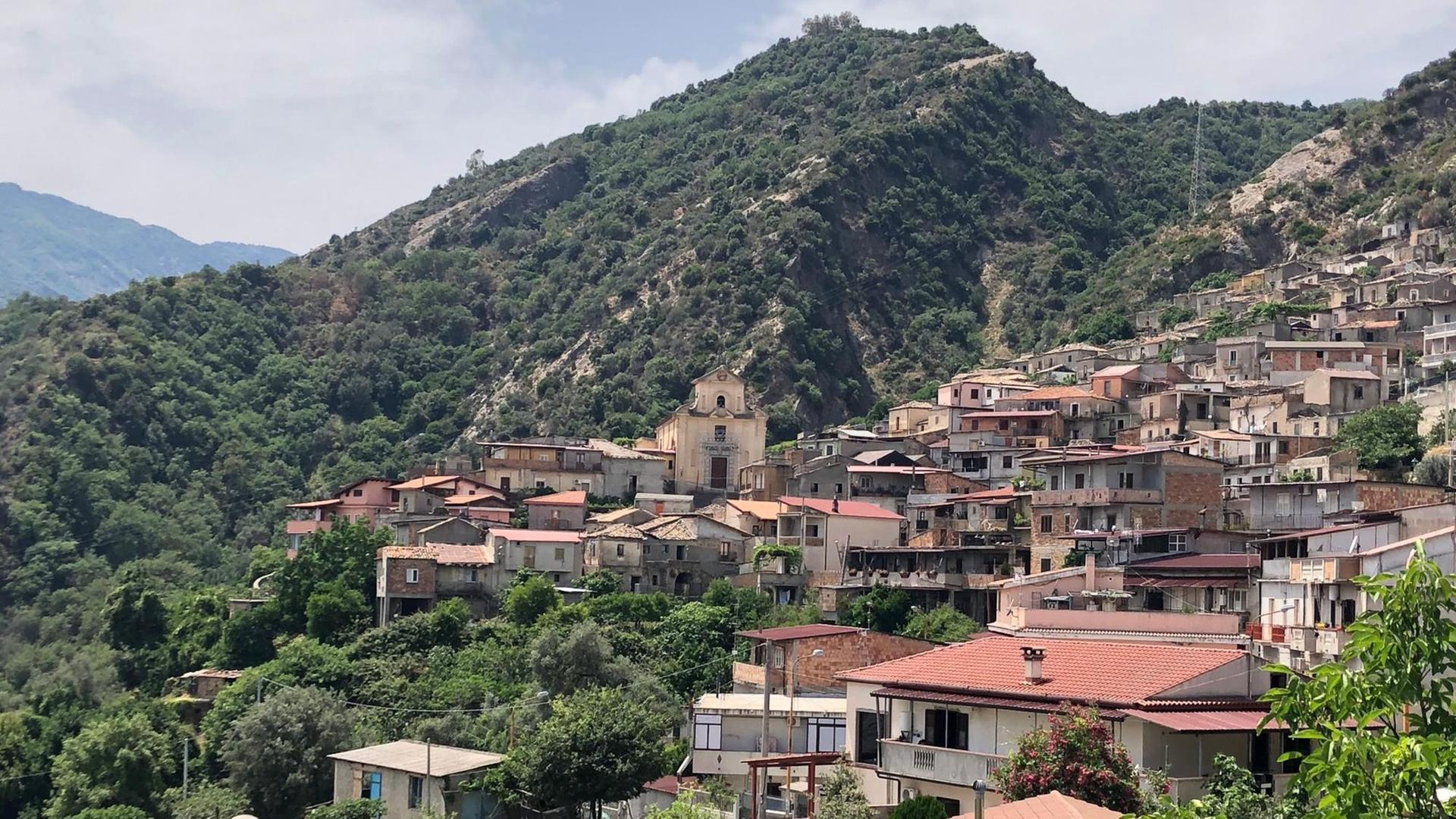 Mafia-Hochburg unter Fremdverwaltung: San Luca in Kalabrien. Zu sehen sind Häuser an einem Berghang mit terracotta-farbigen, flachen Dächern.