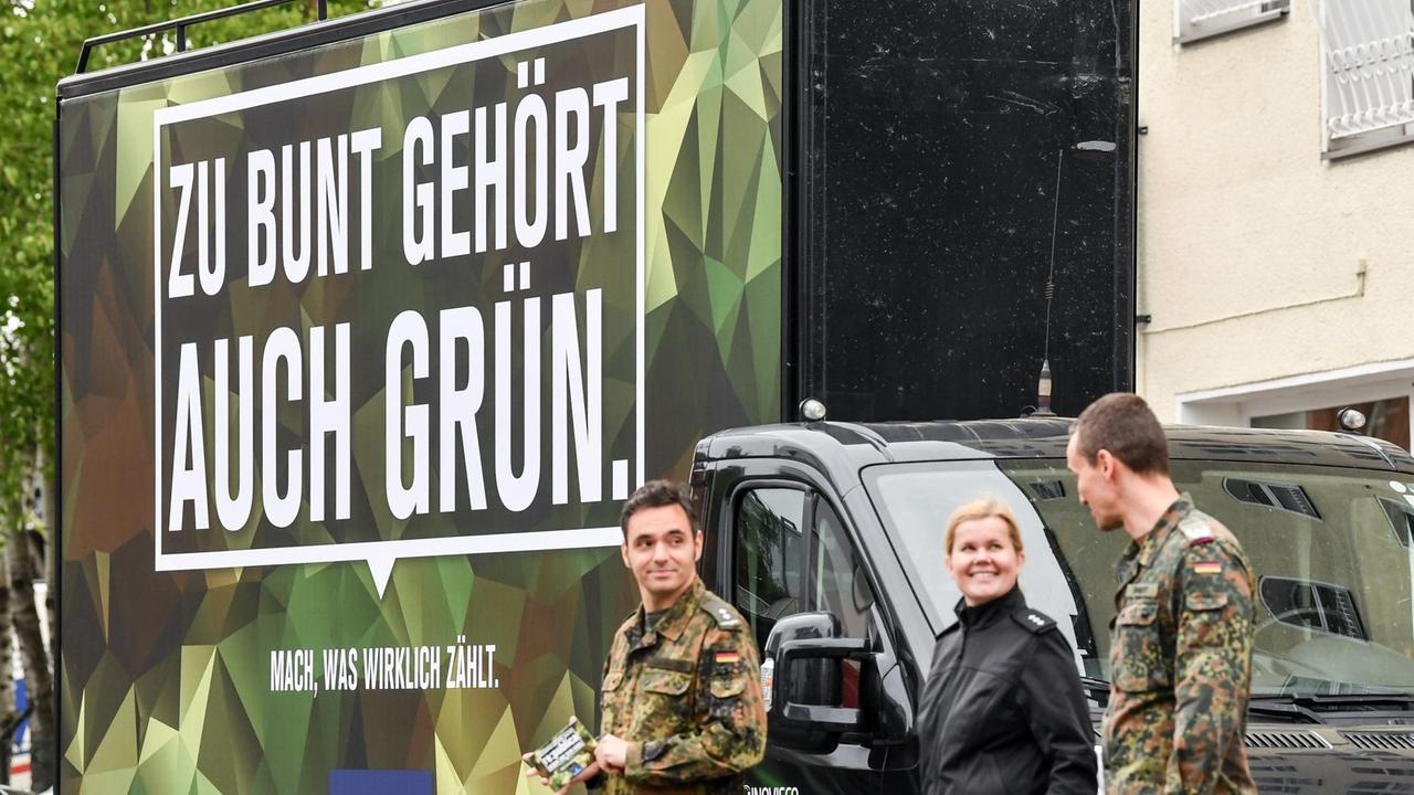 Soldaten der Bundeswehr stehen mit einem Werbeplakat vor den Toren der Internetkonferenz re:publica. 