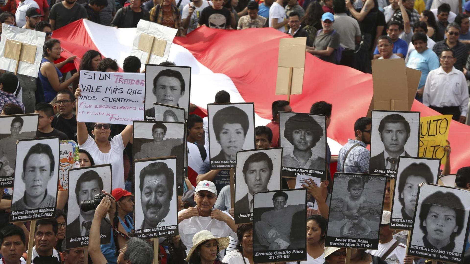 Demonstranten protestieren dagegen, dass der frühere Präsident Perus - Alberto Fujimori - begnadigt wurde. Sie halten Bilder von Menschen hoch, die verschwunden sind, als Fujimori regierte.